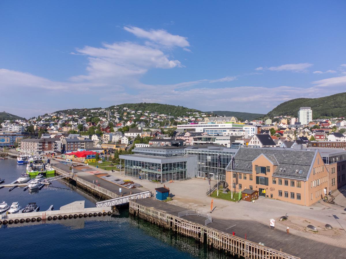 Luftfoto av fasaden til UiT i Harstad med Harstad by i bakgrunnen.
