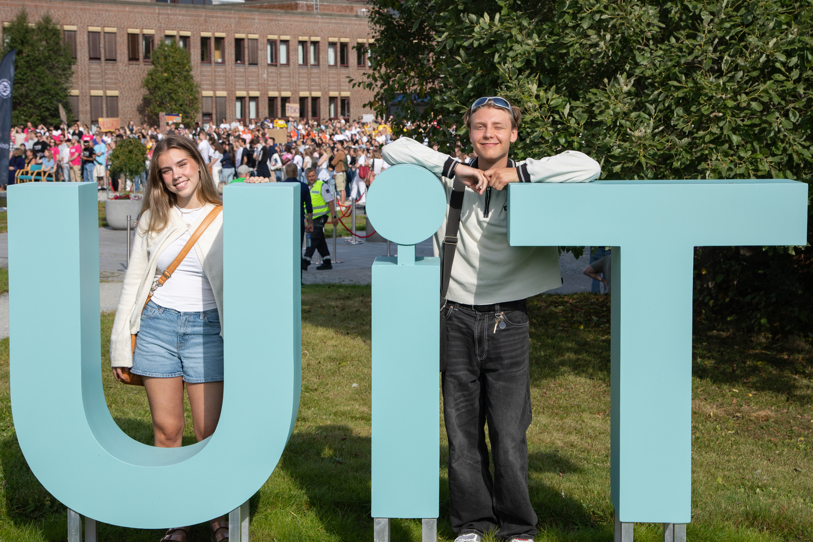 Semesterstart_2024_UIT_25158_Foto_Kaja_Alexandra_Halvei_Larsen.jpg To studenter, mann og kvinne, ved UiT-logo på campus