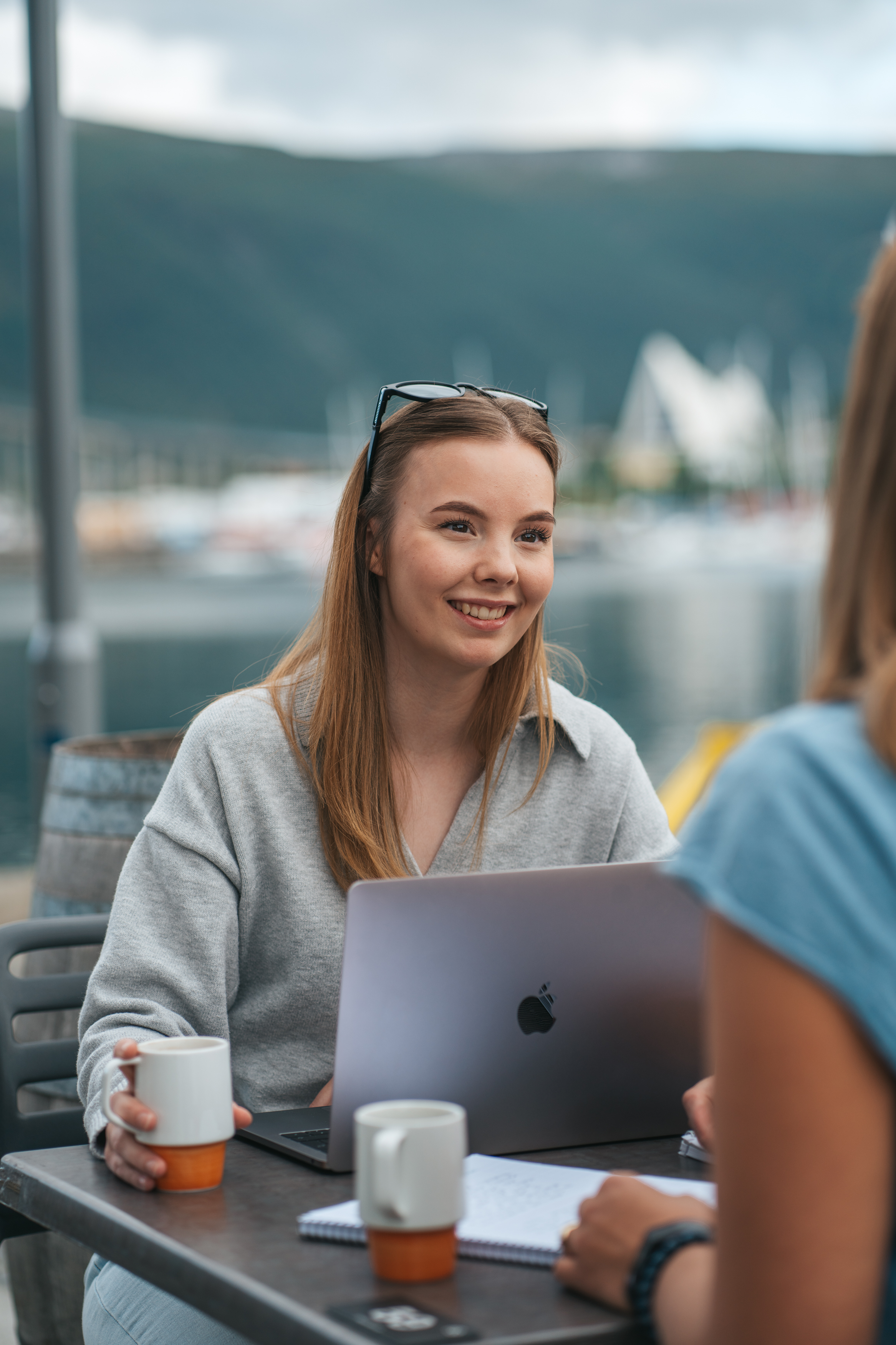 Smilende ung kvinne foran pc utendørs