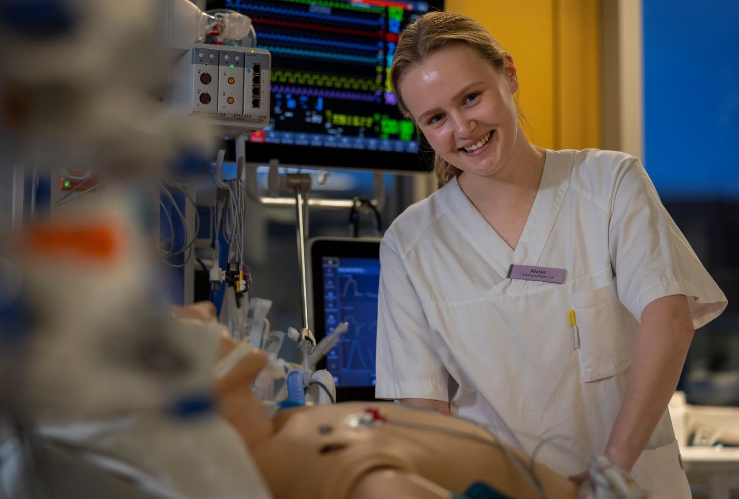 Smilende sykepleierstudent omgitt av medisinsk utstyr