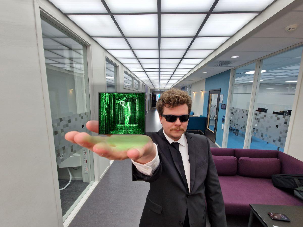 En mann holder en liten skjerm i h&aring;nden