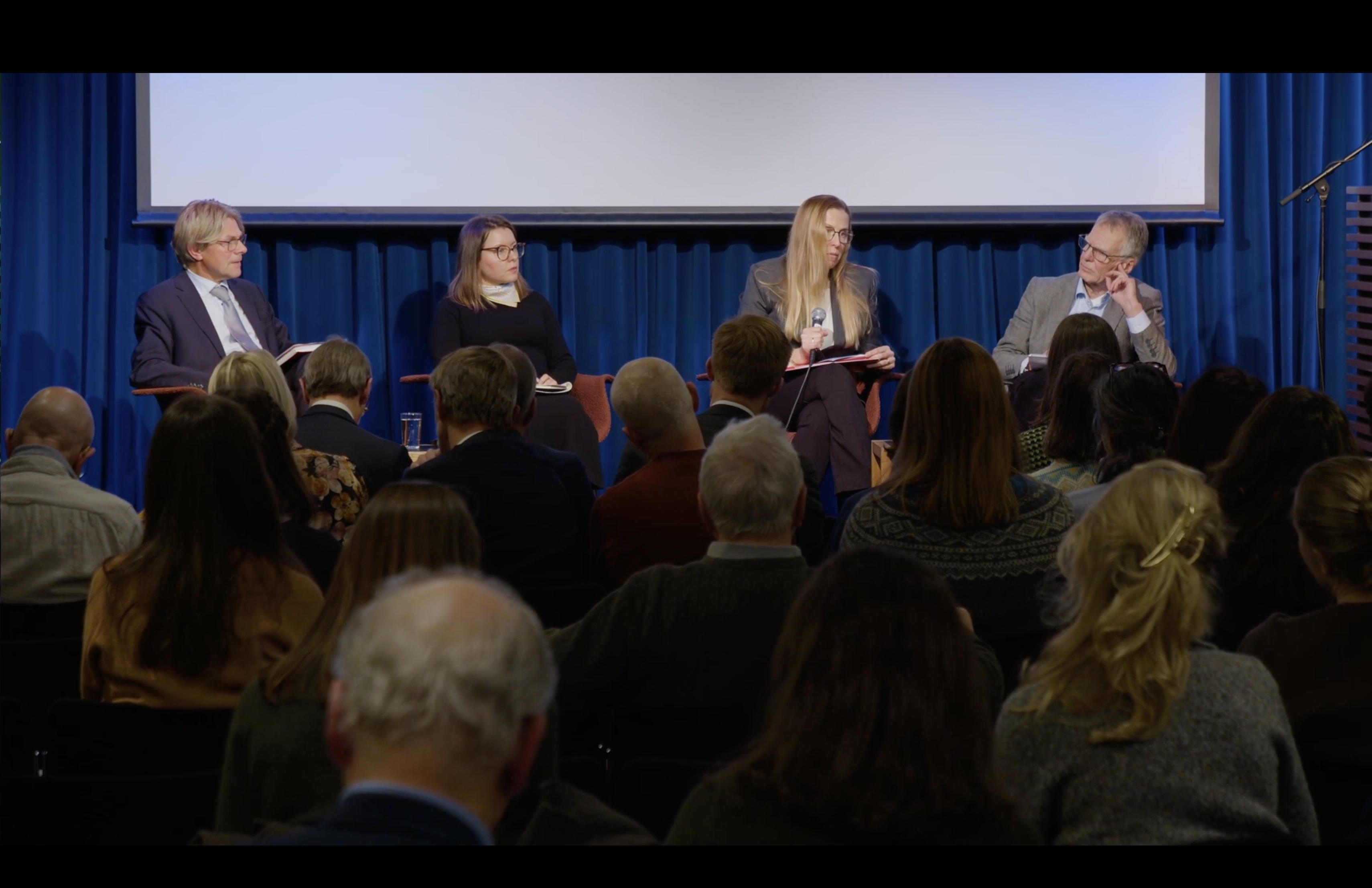 panelists on stage sitting in chairs. 