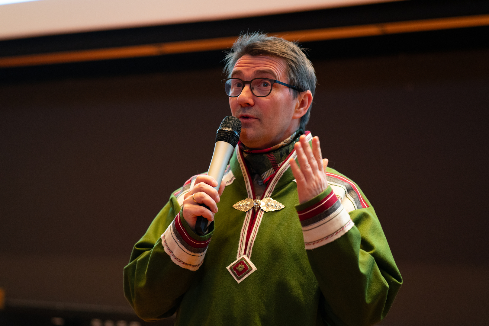 Mann i kofte taler i mikrofon. 