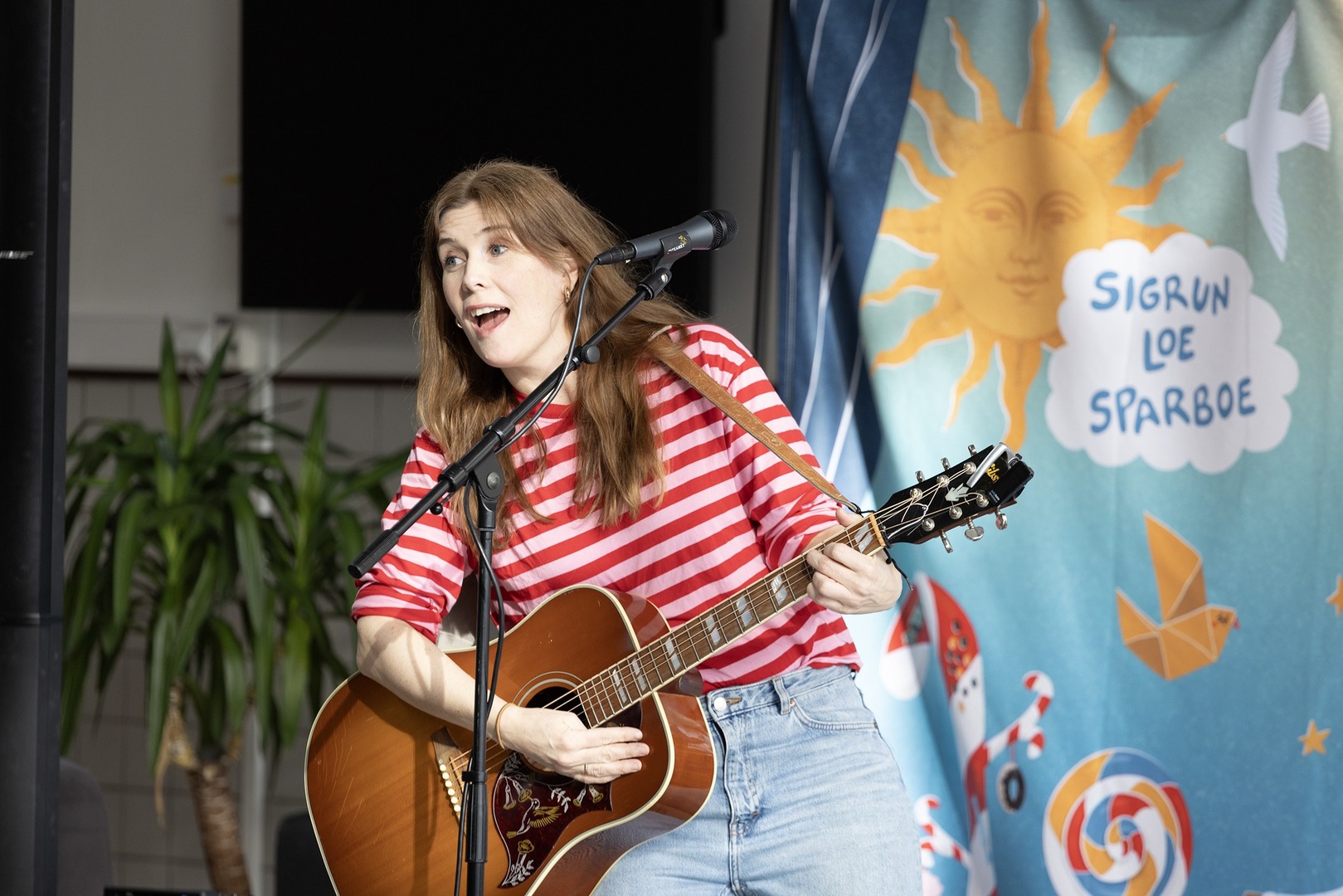 Kvinne spiller gitar p&aring; scene. 