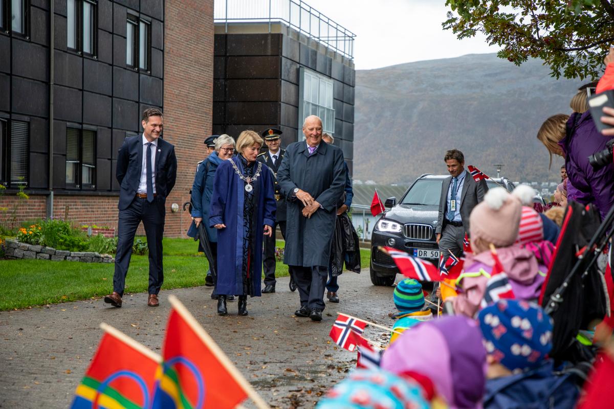 En gruppe mennesker g&aring;r p&aring; en gangsti, barn med flagg langs stien.